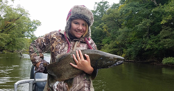 Kid holding large fish with river in background