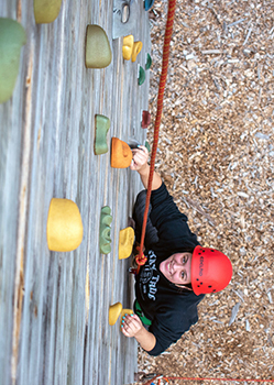 A climbing wall participant from a Becoming an Outdoors-Woman weekend outing is shown.