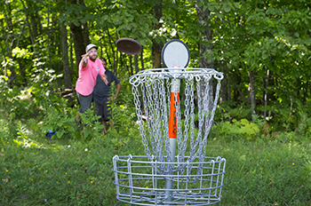 visitor throwing disc at chain basket outdoors