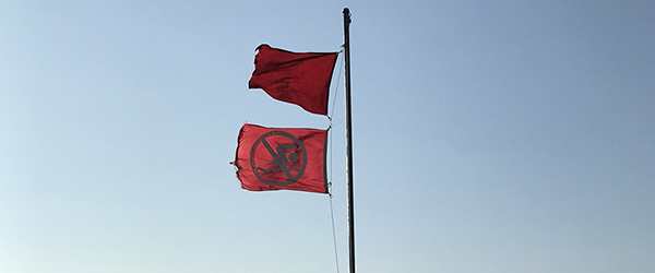 double red flags with blue sky in background