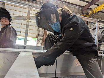 student doing welding work on metal footbridge