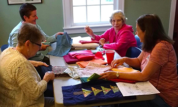 group of people at table working on quilting project