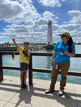 kid holding fish on pole while adult looks on