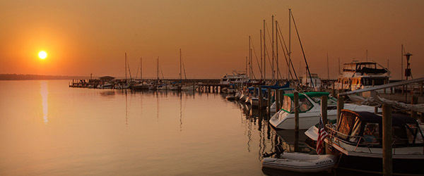 boats in harbor slip with orange sky