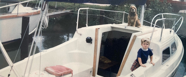 an older photo of a boat, dog and child