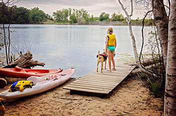 A girl standing with leashed dog on kayak launch on Duck Lake