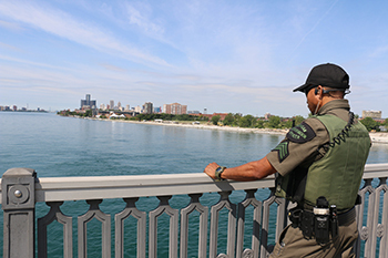 conservation officer standing on bridge looking over Detroit River