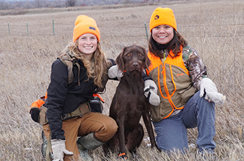 two girls pheasant hunting with dog