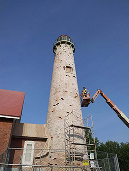 Several men work to fill holes in tower where bricks needed to be replaced.