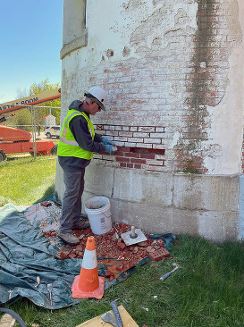 White conical tower showing horizontal spaces where bricks were removed. 
