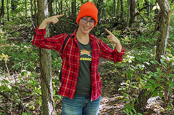 hiker pointing to her hunter orange hat along trail