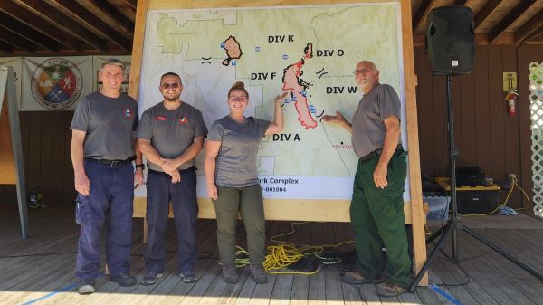 DNR resource analyst Holly Toohey stands in front of a map with other members of her team at a California wildfire. 