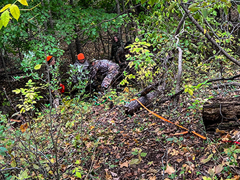 Women work to bring a harvested deer up an embankment.