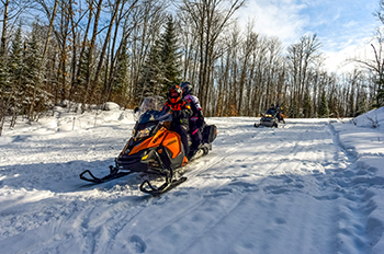 snowmobile riders on snowy trail