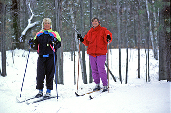 two cross-country skiers under trees