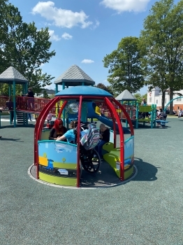 Children playing on an accessible playground during a sunny summer day.