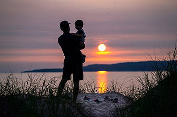 silhouettes of father and child watching sunset