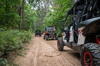 ORVs riding along trail in woods