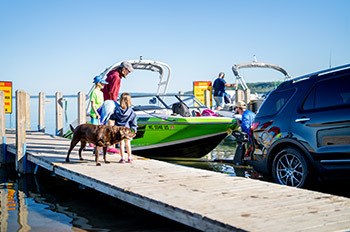 Boaters and leashed dog standing on skid pier waiting to load boat