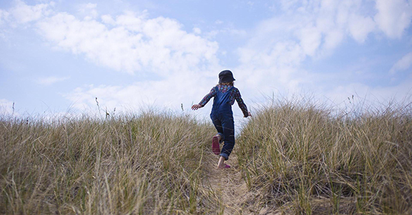 child running on sandy dune trail