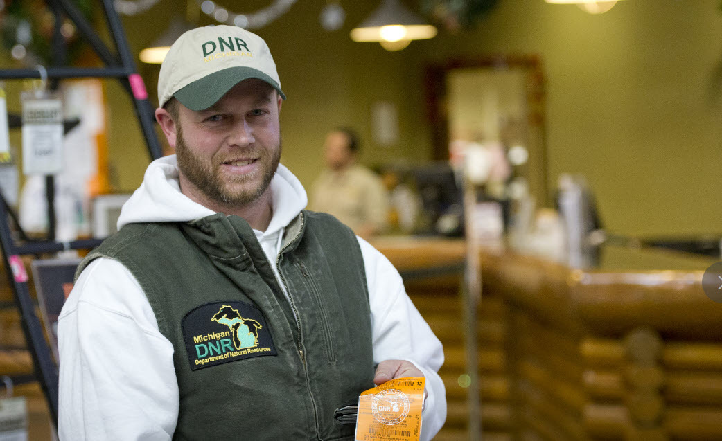 A DNR employee holds a freshly printed hunting license/application. 