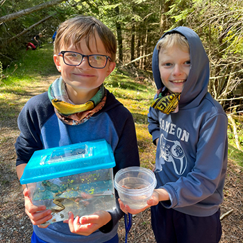 A pair of students smile with a frog