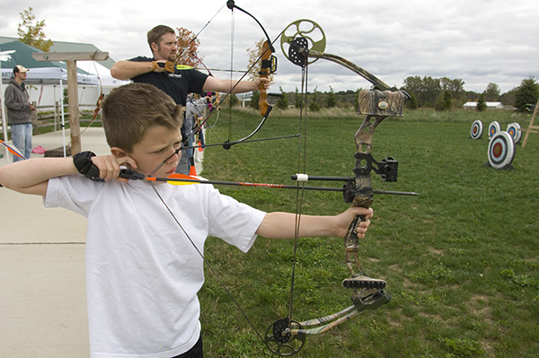 boy and man shooting bows at targets