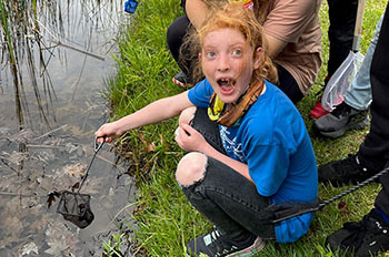 Student dipping net into water looking excited