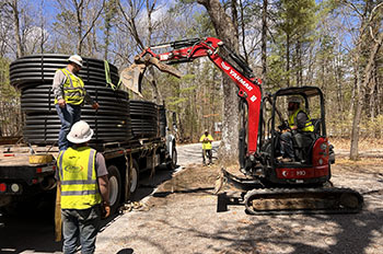 workers in hard hats running lines in park