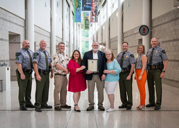 nine people stand in a hall, smiling