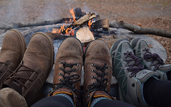 three sets of hiking boots resting on firepit wall