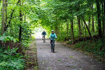two people riding on paved trail with helmets