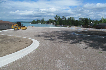 site with new curb and gravel road with lake in background