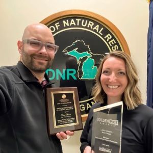 Wildtalk podcast hosts smile with awards from the Association of Conservation Information and Government Social Media Awards