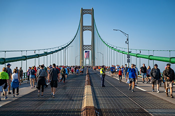 People walking over the Mackinac Bridge in both direction with police officer looking over