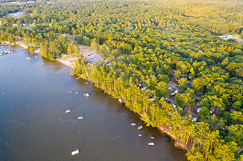 bird's-eye view of water and land featuring trees and campsites