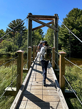 Hikers walk over a bridge at the Mouth of the Two-Hearted River State Forest Campground.