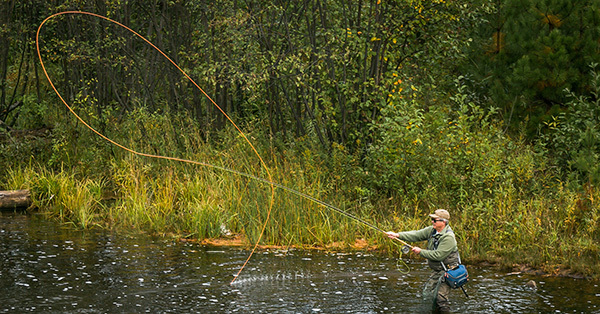 angler fly fishing in stream