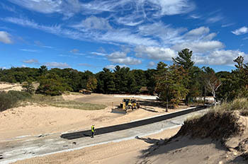 construction crew working on road surrounded by sandy dunes