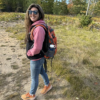 person hiking with backpack on wooded trail in fall