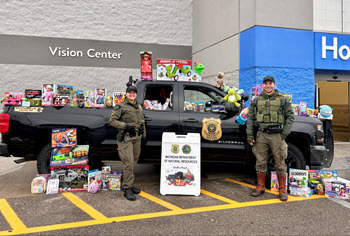 two officers standing by truck with toys