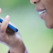 A woman records a voice memo on her phone. 