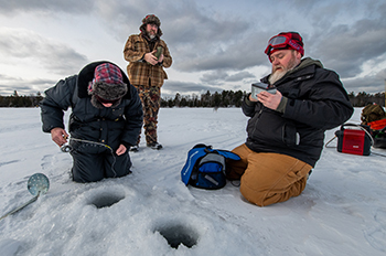 three anglers prepping ice fishing hole