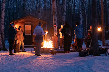 group of people standing around campfire in woods