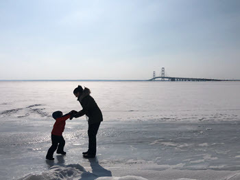 Child and adult holding hands on ice