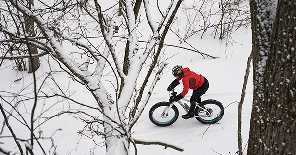 fat-tire biker riding through snowy forest