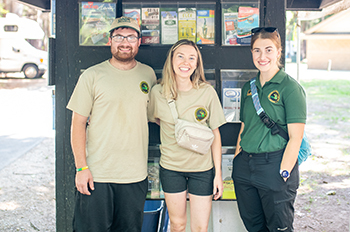 two host and a ranger standing in front of kiosk