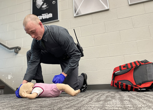 Man evaluating a training doll during a first-aid scenario.