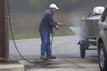 a boater spraying boat to prevent invasive species