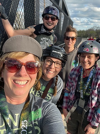 a small group of smiling women in Happy Little T-shirts, bike helmets and sunglasses take a break during the Happy Little 5K